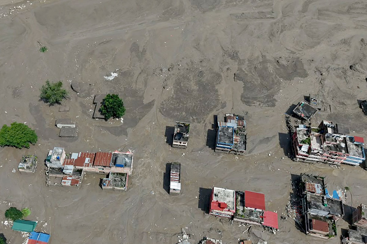 Houses lie partially submerged in muddy water along a riverside after flash floods at Trishuli Bazar in Nepal's Nuwakot district on August 26, 2026. (Photo by Prabin RANABHAT / AFP)