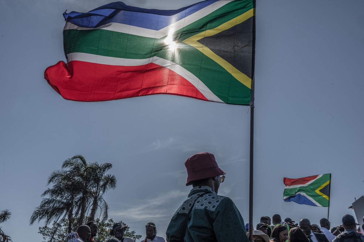 March and March Movement members wave South African flags as they protest outside the Durban International Convention Centre (ICC) under the theme 