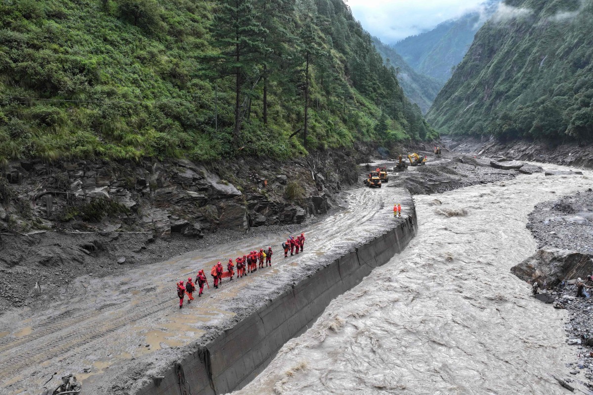 Fire and rescue personnel conduct search and rescue operations on a section of a road leading to Gyirong Port which was damaged after a mudslide two days earlier, in Gyirong County, in China's western Tibet region on August 28, 2026. (Photo by CNS / AFP)