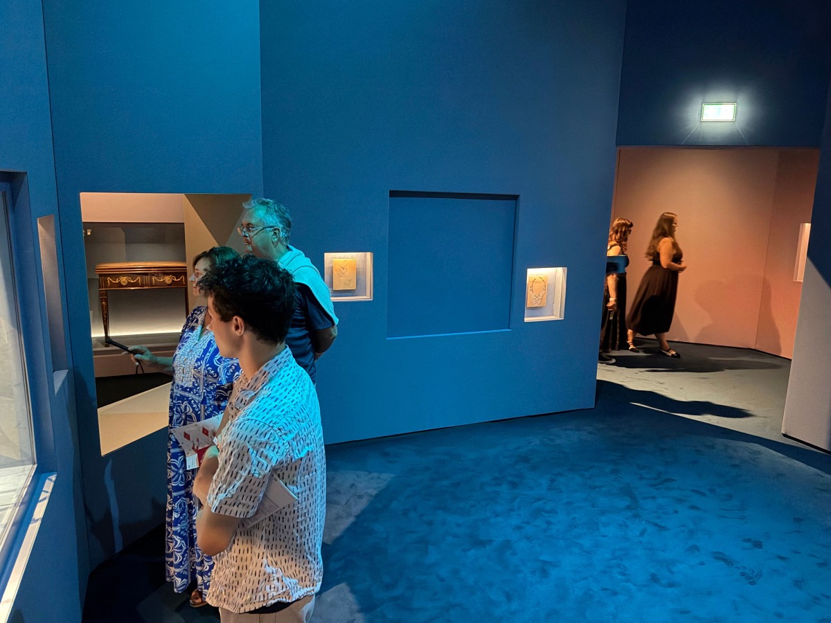 Visitors look at exhibits near a blue panel covering the area where a display case was smashed and a Van Cleef and Arpels necklace was stolen at Vienna's Museum of Applied Arts (MAK), in Vienna, Austria, on August 28, 2026. Photo by Jeremy AUDOUARD / AFP