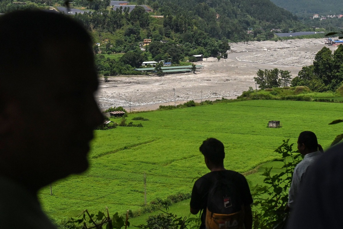 Residents look at the Trishuli River as they take shelter at an elevated place after a flood warning in the Pipaltar area of Nepal's Nuwakot district on August 28, 2026. (Photo by Arun SANKAR / AFP)