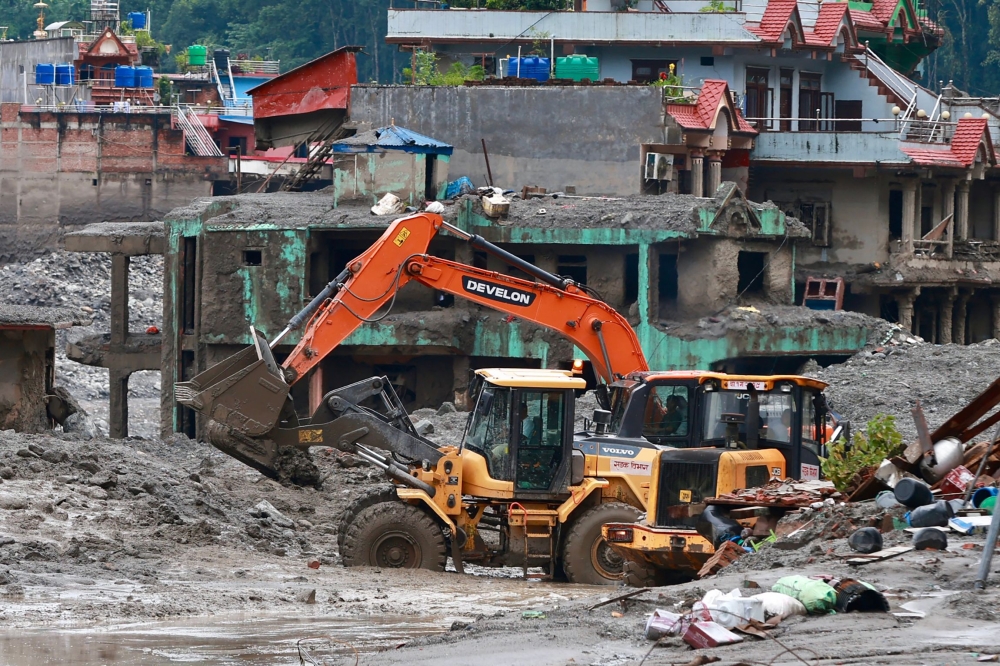 Workers use excavators to clear the mud at the Dhunge Bazaar in Nepal's Nuwakot district on August 29, 2026 after flash floods and landslides hit the Nepal-Tibet border. (Photo by PRABIN RANABHAT / AFP)