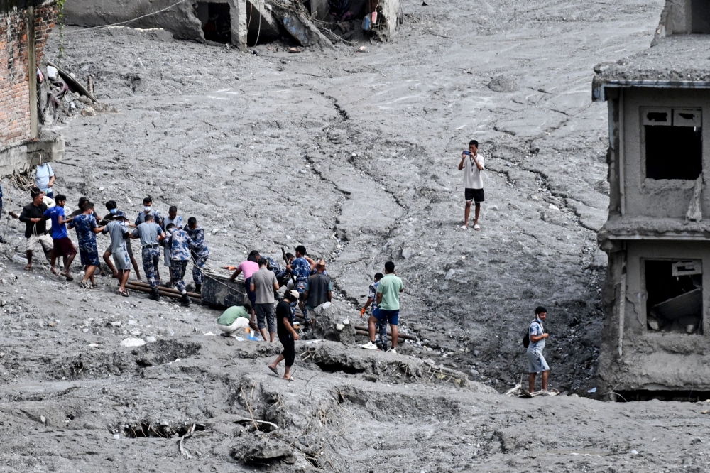 Rescue personnel pull out a locker from a deluged bank after flash floods at Trishuli Center in Nepal's Nuwakot district on September 1, 2026. T(Photo by Arun SANKAR / AFP)