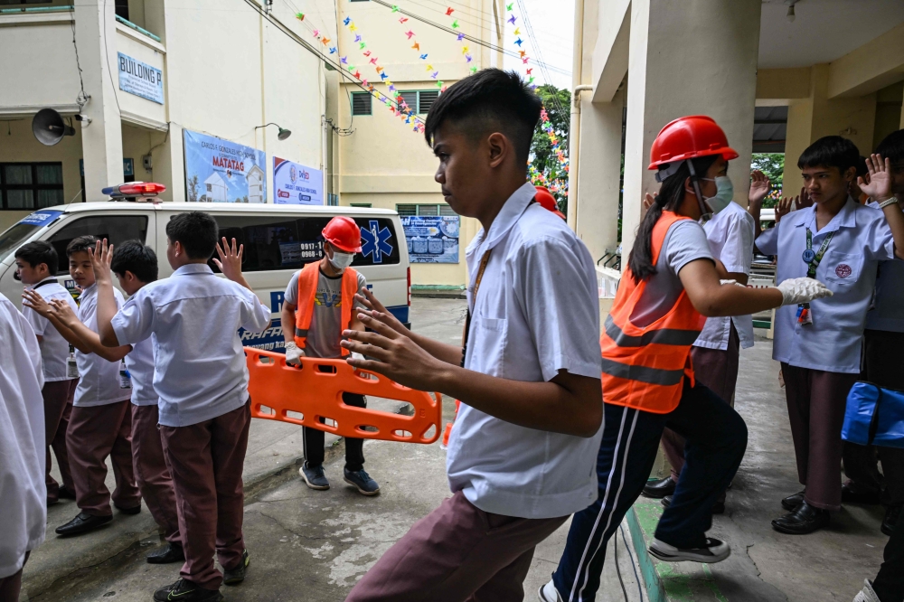 Students raise their hands as they evacuate during a nationwide school drills to safeguard students from armed intruders, at a school in San Rafael, Bulacan on September 3, 2026. (Photo by Jam STA ROSA / AFP)