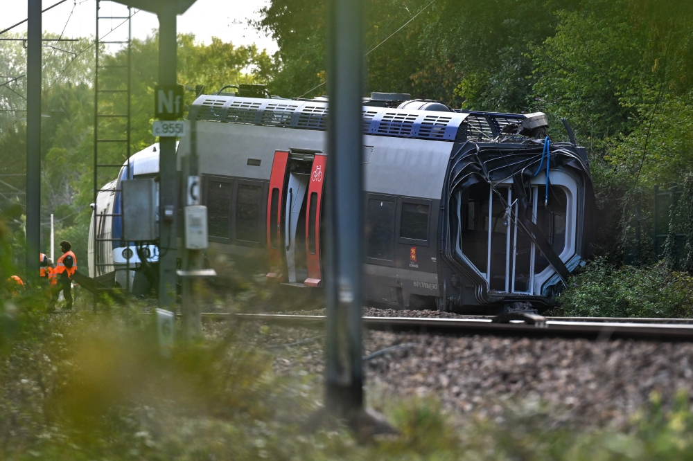 SNCF workers stand next to a derailed train carriage in Cléon, northwestern France, on September 12, 2026, the morning after the train derailed. (Photo by Guillaume Saligot / AFP)