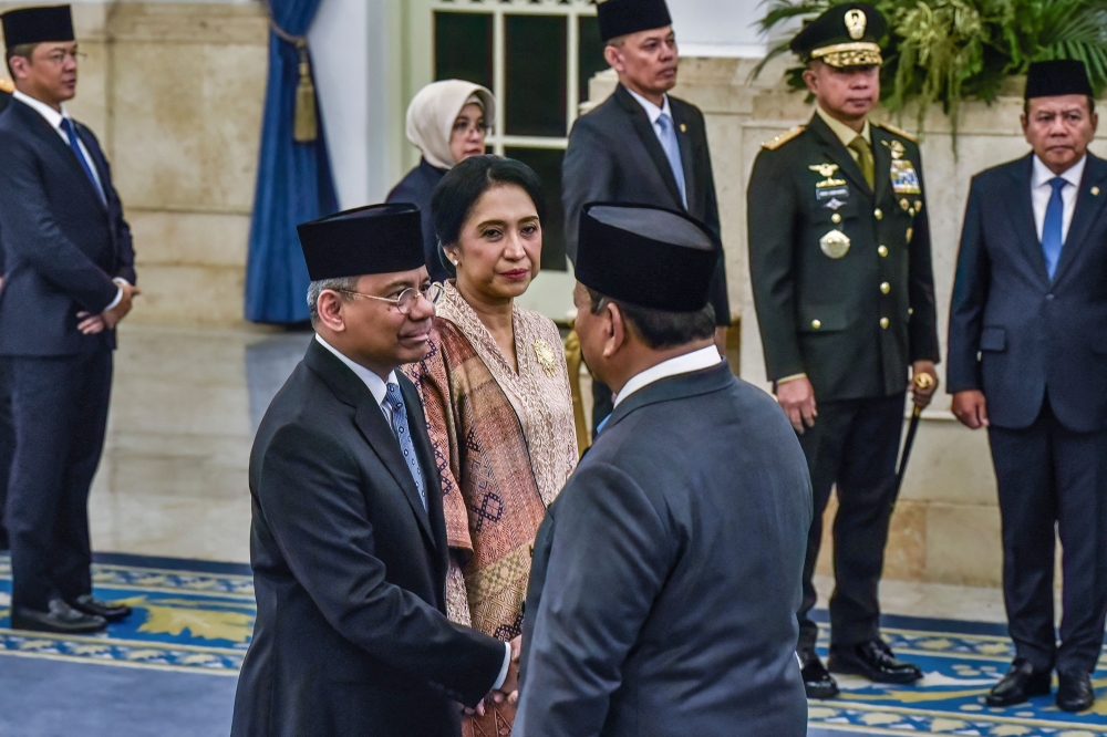 Indonesia's President Prabowo Subianto (R) shakes hands with newly appointed Finance Minister Suahasil Nazara (L) past his wife Christina Pusporini Messakh (C) during a swearing-in ceremony at the presidential palace in Jakarta on September 14, 2026, following a cabinet reshuffle. Indonesian president Prabowo Subianto removed Finance Minister Purbaya Yudhi Sadewa from his position, naming his deputy as the new minister. (Photo by FATIH MUBAROK / AFP)