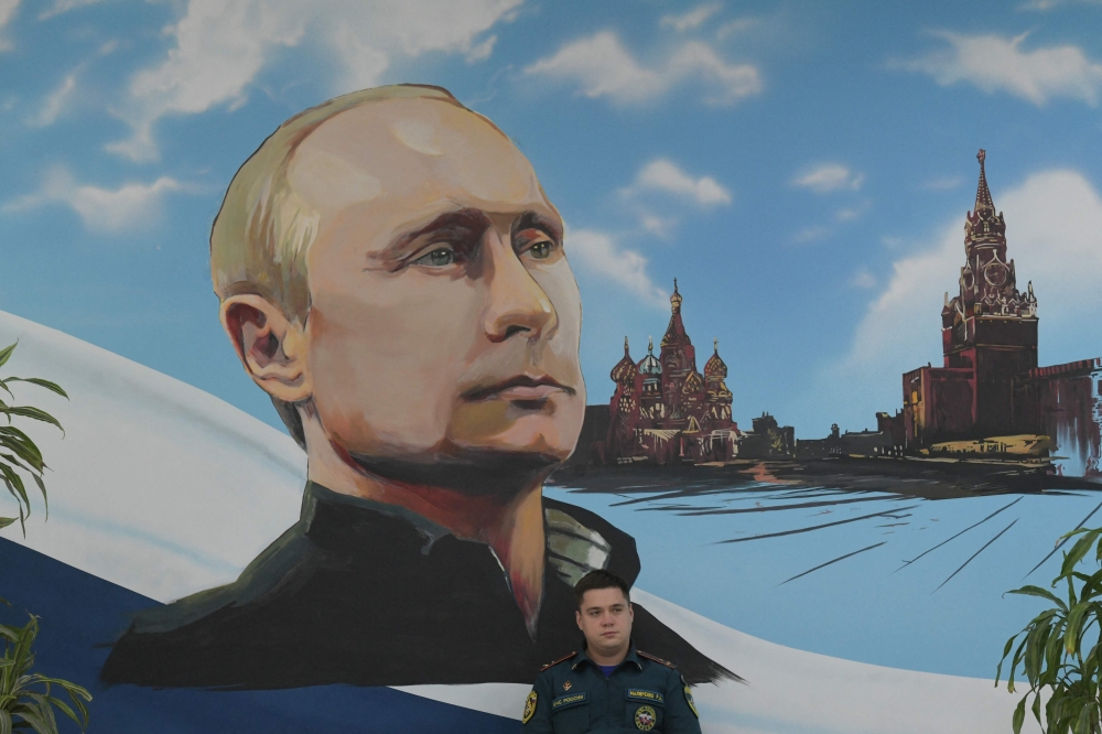 A serviceman of Russia's Emergencies Ministry sits under a mural depicting Russian President Vladimir Putin during Russia's parliamentary election at a polling station in Donetsk, Russian-controlled Ukraine, on September 20, 2026. (Photo by AFP)