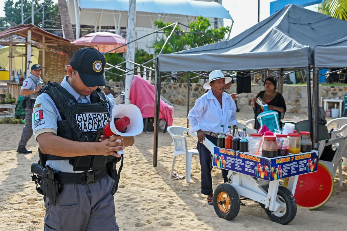 A member of the Mexican National Guard makes an announcement to residents and visitors about the approach of Hurricane Polo along a beach in Acapulco, Guerrero state, Mexico, on September 21, 2026. (Photo by Francisco Robles / AFP)