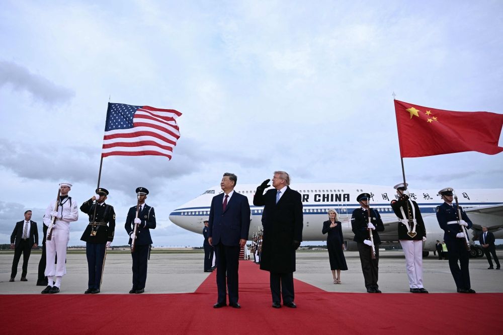 US President Donald Trump reacts after a B1 bomber flew past during the national anthems while he greeted Chinese President Xi Jinping upon his arrival at Joint Base Andrews in Maryland on September 23, 2026. (Photo by Brendan Smialowski / AFP)