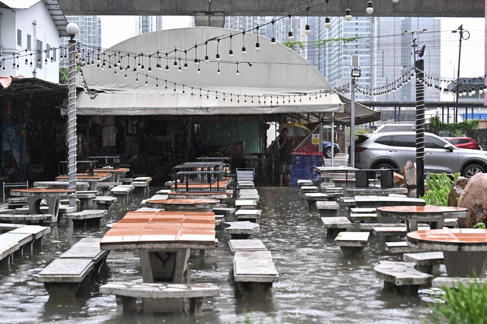 A man looks out from a flooded restaurant in Bangkok on September 26, 2026. (Photo by Lillian Suwanrumpha / AFP)