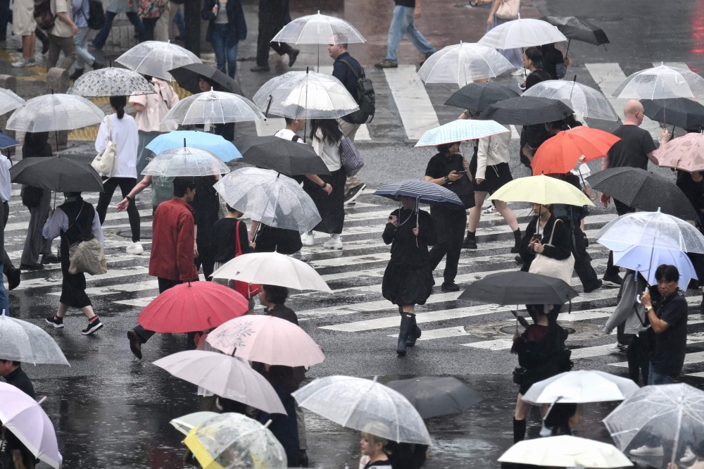 (Files) Pedestrians with umbrellas walk on a crossing as rain falls in Tokyo's Shibuya district on September 20, 2026. (Photo by Rie Kikuchi / AFP)