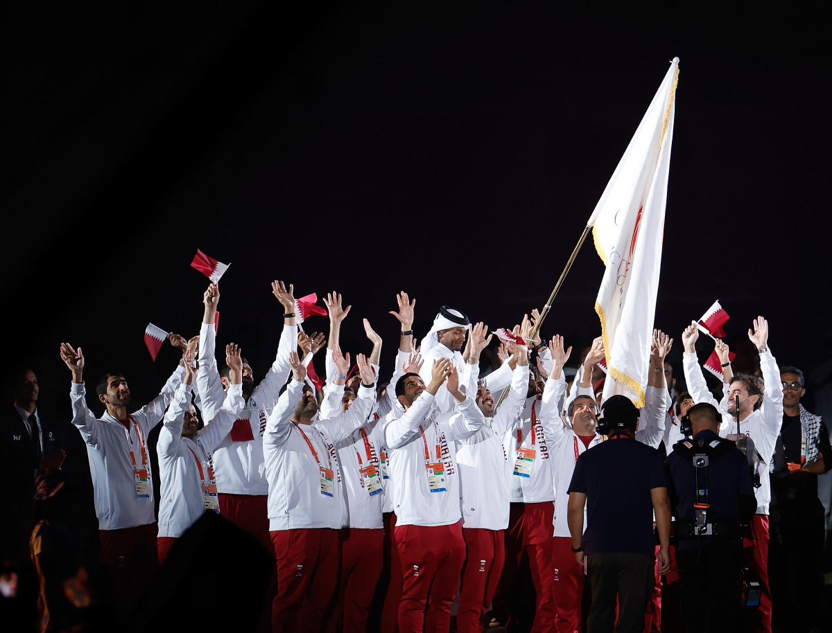 Members of the Qatar delegation celebrate as high jump legend Mutaz Barshim carries the OCA flag during the closing ceremony. (Xinhua)