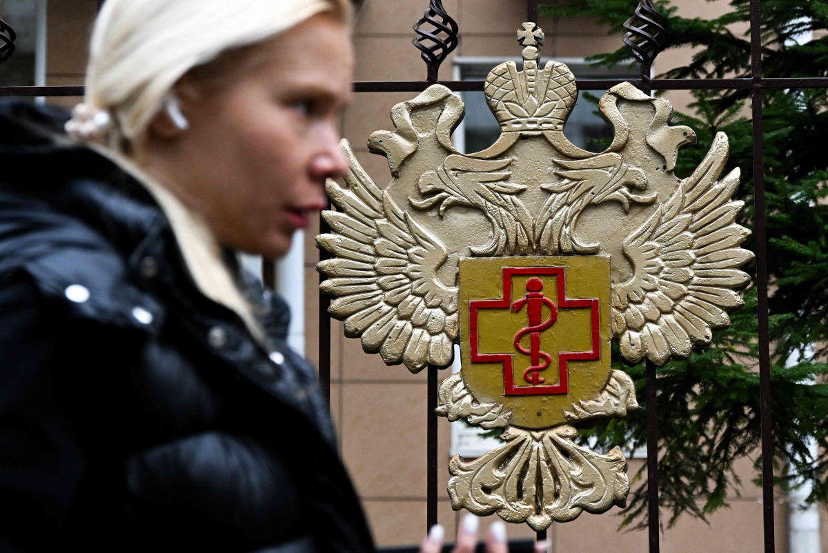 A woman walks past the logo of Russia's consumer and health watchdog Rospotrebnadzor sitting on its grounds' fencing in Moscow on October 5, 2026. Photo by Igor IVANKO / AFP