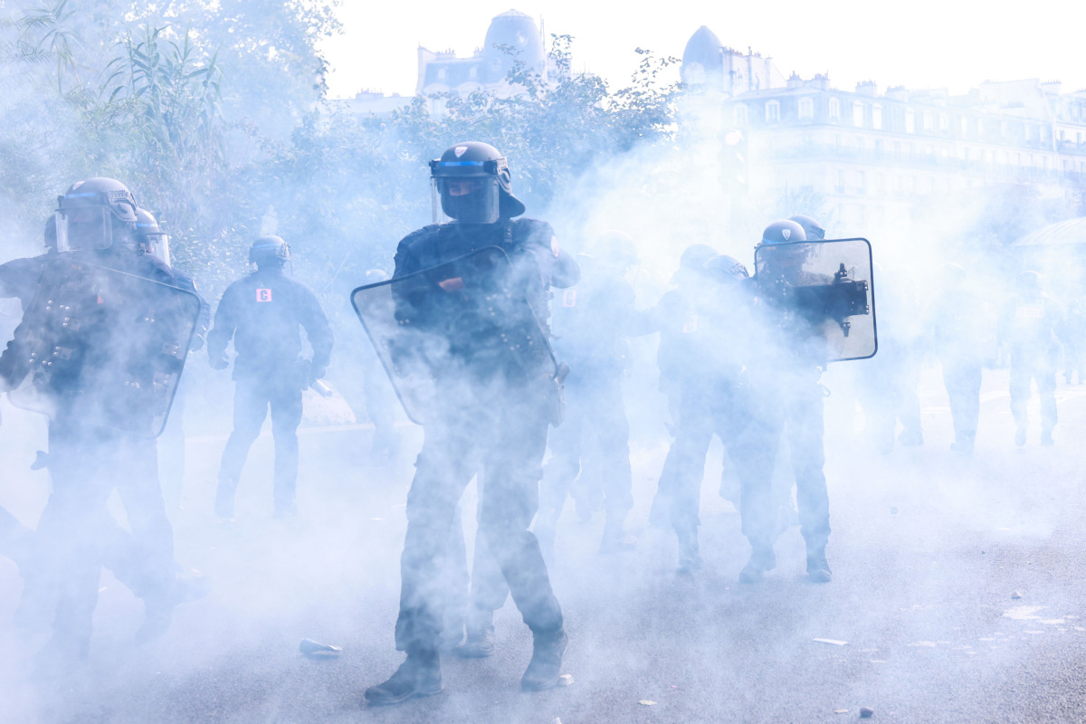 Police officers stand in the smoke during a demonstration of high-school students, in Paris on October 6, 2026, as part of a nationwide protest movement over learning conditions. (Photo by Kenzo TRIBOUILLARD / AFP)