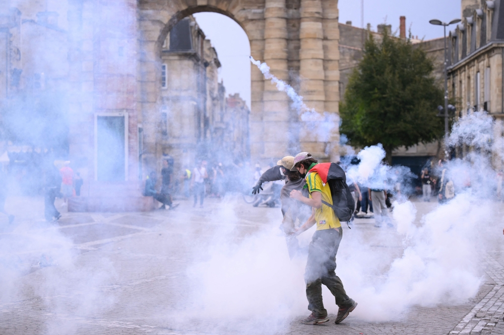 Protesters stand amid tear gas fired by police during demonstration part of a nationwide day of actions called by high-school students in Bordeaux, southwestern France, on October 6, 2026. (Photo by Christophe ARCHAMBAULT / AFP)
