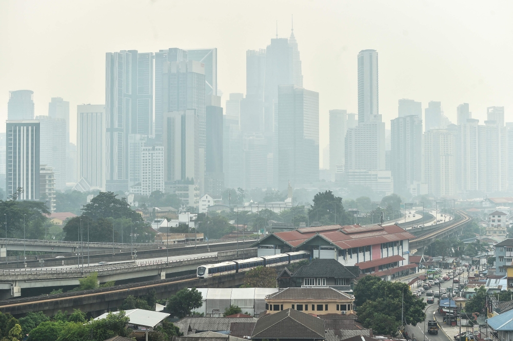 A dense layer of haze blankets the Kuala Lumpur skyline as a light rail train passes through the city on October 7, 2026.  (Photo by Arif Kartono / AFP)