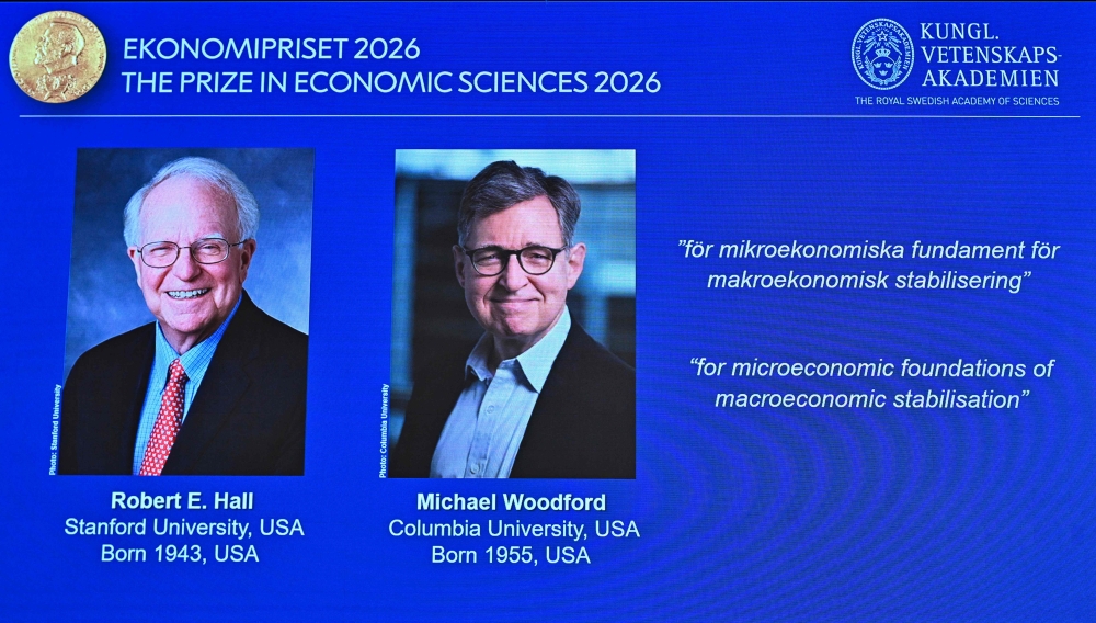 The winners of the 2026 Sveriges Riksbank Prize in Economic Sciences in Memory of Alfred Nobel, Robert E Hall (L) and Michael Woodford, are displayed on a screen at the Royal Swedish Academy of Sciences in Stockholm on October 12, 2026. Photo by Anders Wiklund / TT NEWS AGENCY / AFP 
