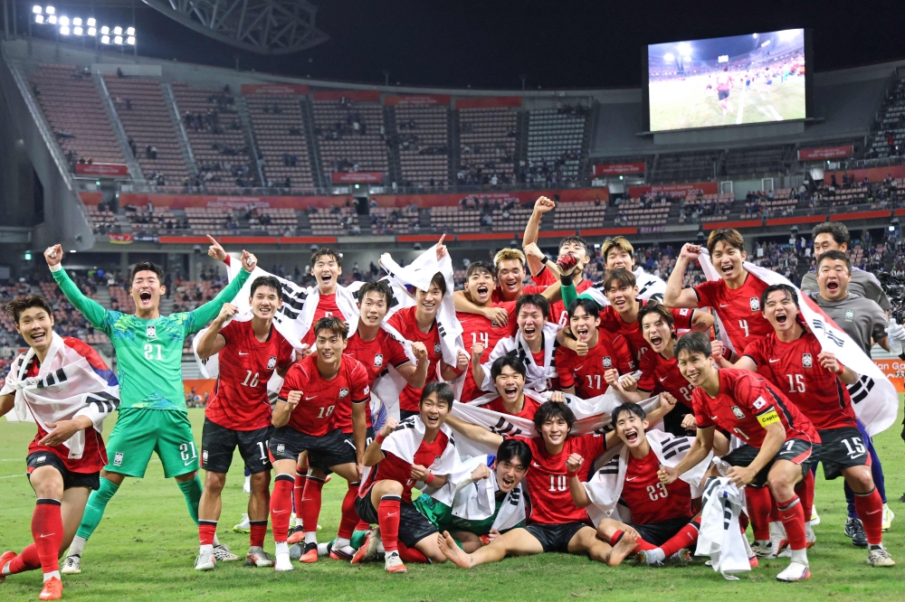 This picture taken on October 3, 2026 shows South Korean players celebrating after winning the gold medal in the men's football final match between Japan and South Korea in the 2026 Asian Games at Toyota Stadium in Toyota. (Photo by YONHAP / AFP) 