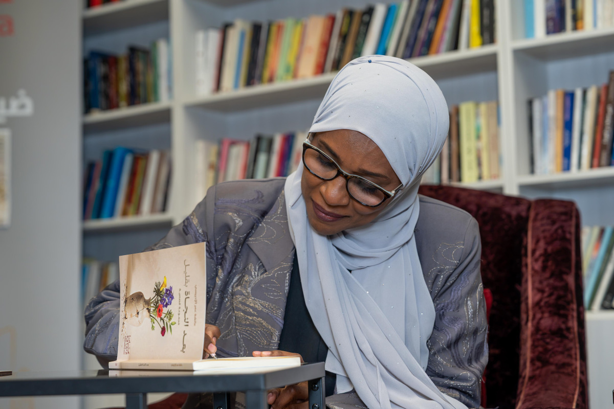 Aisha Al-Idrissi signs a copy of her book for a visitor.