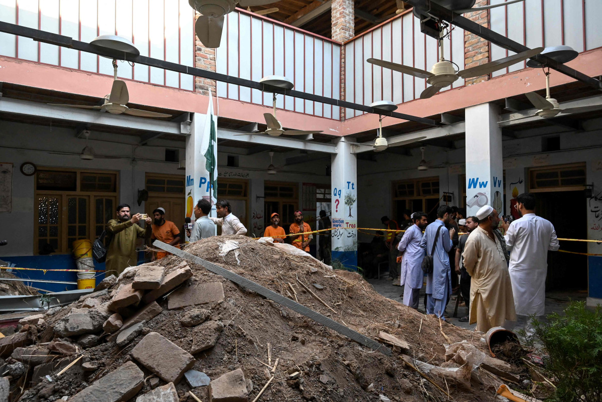 People gather around debris and rubble lying in the courtyard of a school following a roof collapse, in Peshawar on October 15, 2026. Photo by Abdul MAJEED / AFP