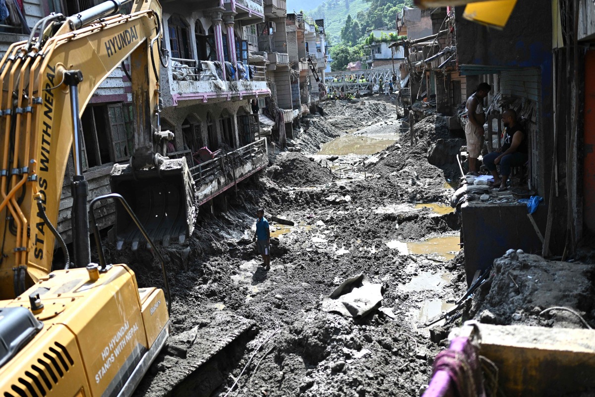 A man operates a backhoe to clean a street in the aftermath of flash floods at Devighat in Nepal's Nuwakot district on September 8, 2026. Photo by Pedro PARDO / AFP