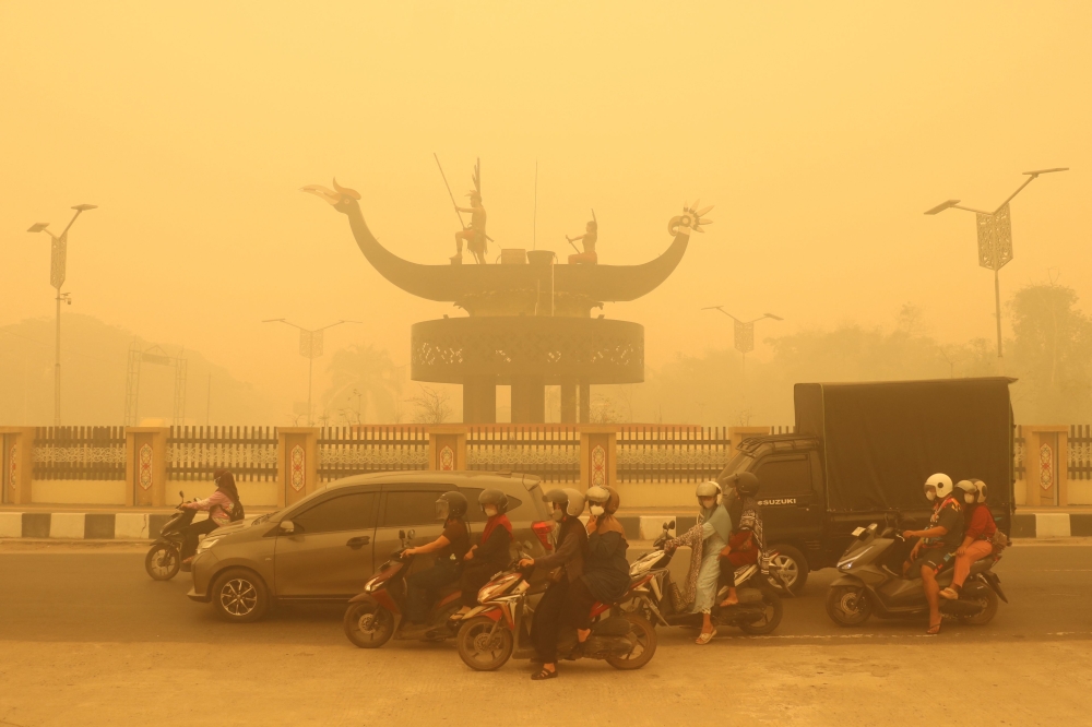 Motorcyclists wearing a face mask ride amid thick haze from forest and land fires in the region in Palangkaraya, Central Kalimantan, on October 24, 2026. (Photo by REINA / AFP)