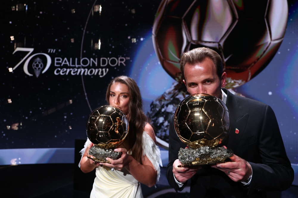 Spain and Barcelona midfielder Alexia Putellas and England and Bayern Munich forward Harry Kane kiss their trophies on stage after receiving their Ballon d'Or awards on October 26, 2026. (Photo by Franck Fife / AFP)