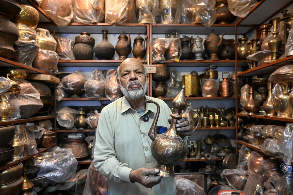 Antique dealer Ahsan Shakeel shows an artefact at his shop selling vintage items in Rawalpindi on October 20, 2026. Photo by Farooq Naeem / AFP
