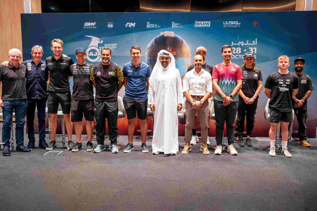 QMMF President Abdulrahman Al-Mannai and QMMF Executive Director Amro Al-Hamad pose for a photo with drivers and riders.
